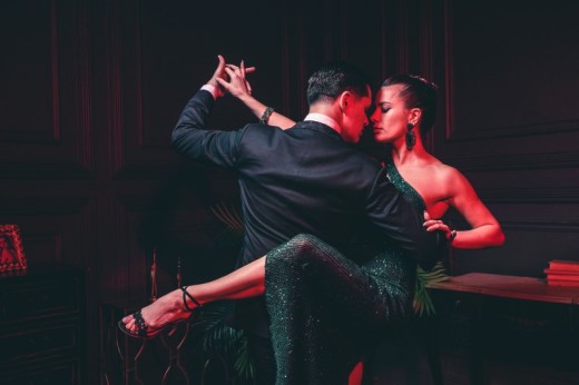 A couple performing an intimate and dramatic Argentine tango dance pose in a dimly lit venue.