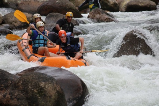 A group of people white water rafting through fast-flowing rapids surrounded by large rocks.