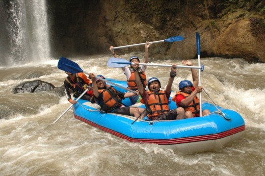 Group of people enjoying a white-water rafting adventure near a waterfall.