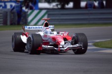 A red and white Formula One race car navigating a turn on a circuit track.