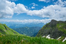 Lush green mountain peaks under a bright blue sky filled with white clouds.