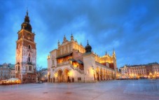 The illuminated Cloth Hall and Town Hall Tower in Kraków's Main Market Square at dusk.
