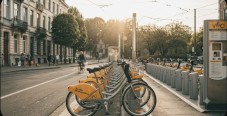 A row of yellow rental bicycles parked at a city docking station during sunset.