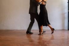 A couple dancing tango on a polished floor in a minimalist studio.