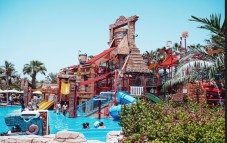 Children and families enjoy an ancient-themed water playground with multiple slides and a large tipping bucket.