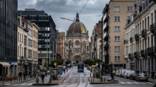 A tram travelling down a city street in Brussels towards the St. Mary's Royal Church.